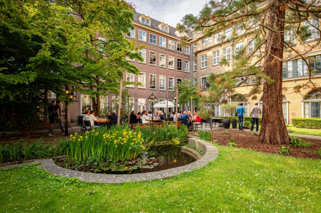 Binnentuin van Loetje Leiden met terras, vijver en veel groen.