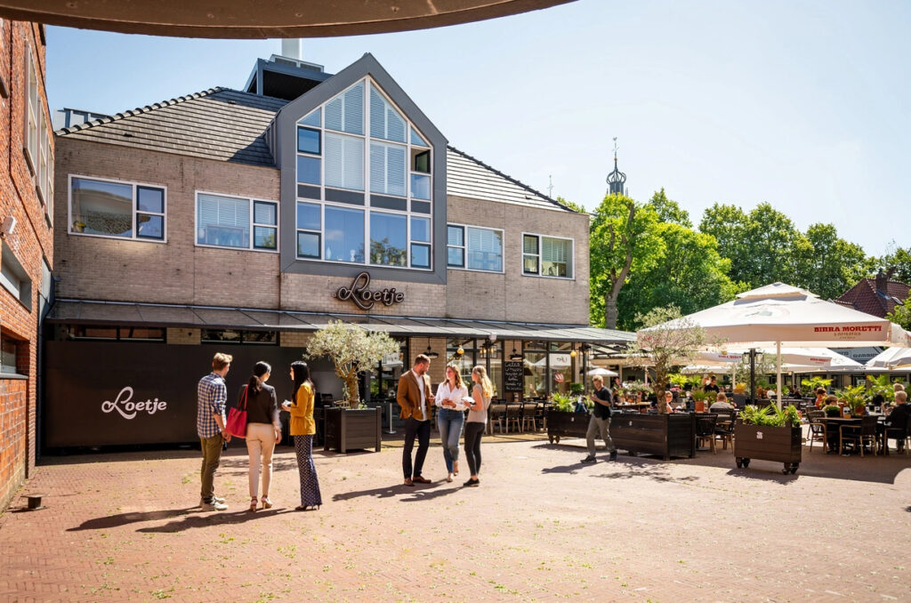 Entree en terras van Loetje Bergen met gasten op een zonnige dag.
