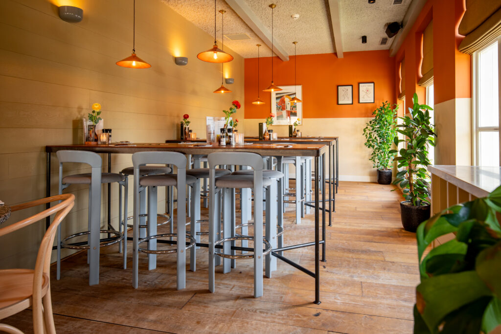 Hoge tafels en stoelen in het kleurrijke interieur van Loetje Breukelen.