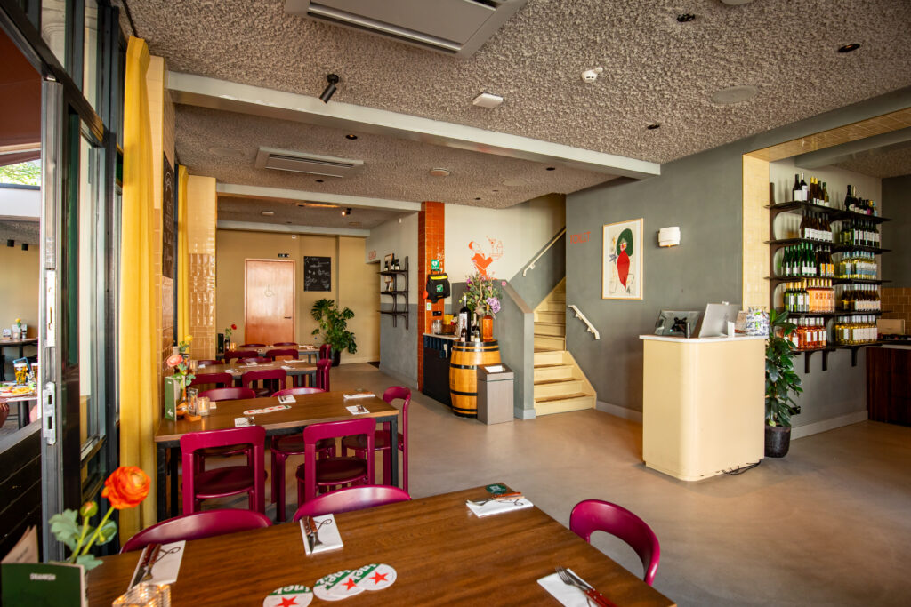 Entree en restaurantgedeelte van Loetje Breukelen met gedekte tafels en kleurrijke stoelen.
