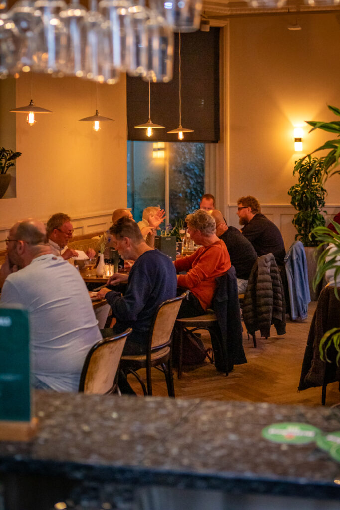 Gasten genieten van een diner aan lange tafels in het sfeervolle restaurant Loetje Leeuwarden.