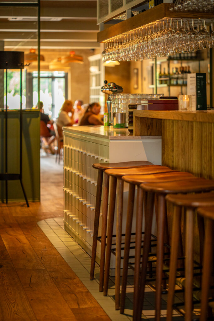 Bar van Loetje Vught met houten barkrukken en hangende wijnglazen.