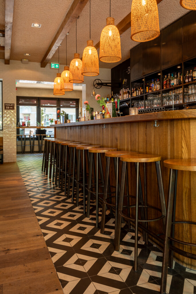 Bar van Loetje De Pijp met houten barkrukken en hanglampen.
