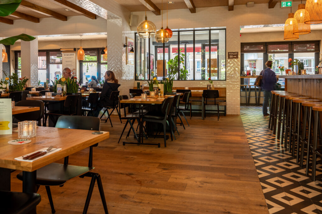 Interieur van Loetje De Pijp met tafels, bar en houten inrichting.