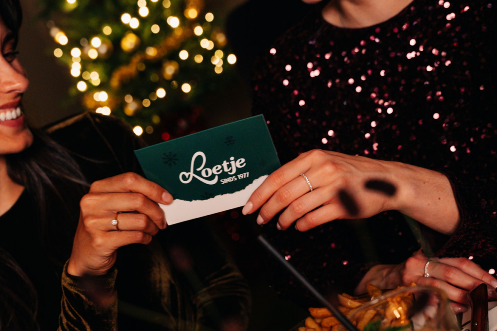 Gasten met een Loetje cadeaukaart tijdens een feestelijk kerstdiner.