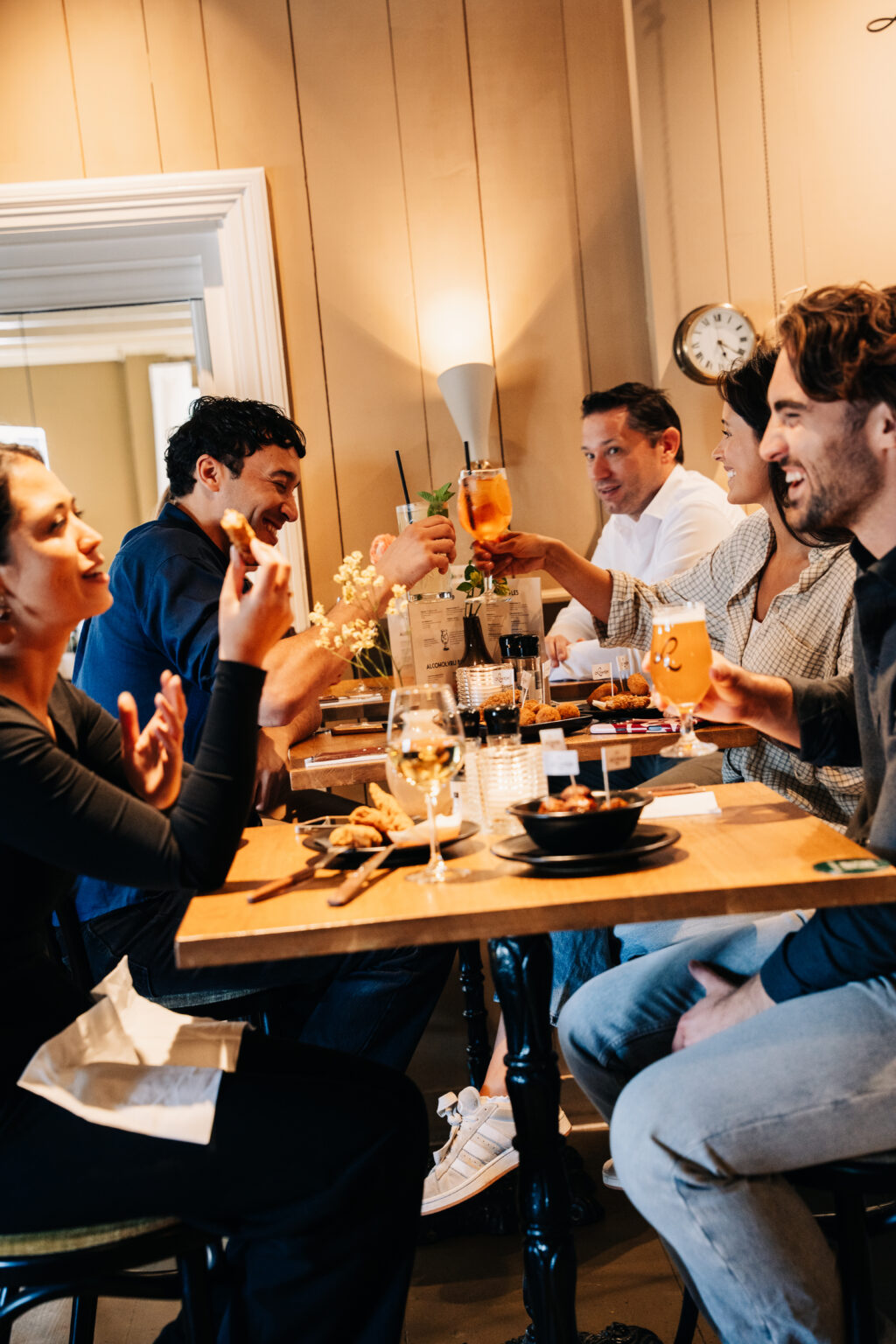 Gezelschap proost met drankjes aan tafel tijdens een gezellige borrel bij Loetje.