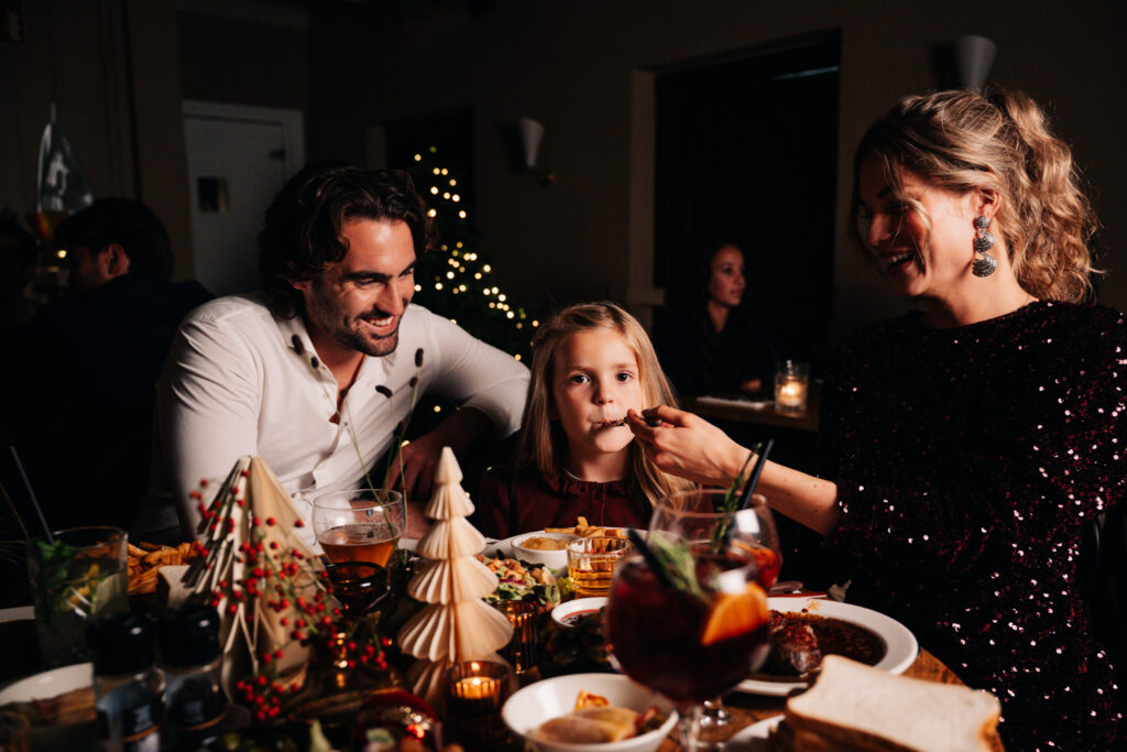 Dochter neemt hap van de feestelijke maaltijd tijdens het kerstdiner bij Loetje