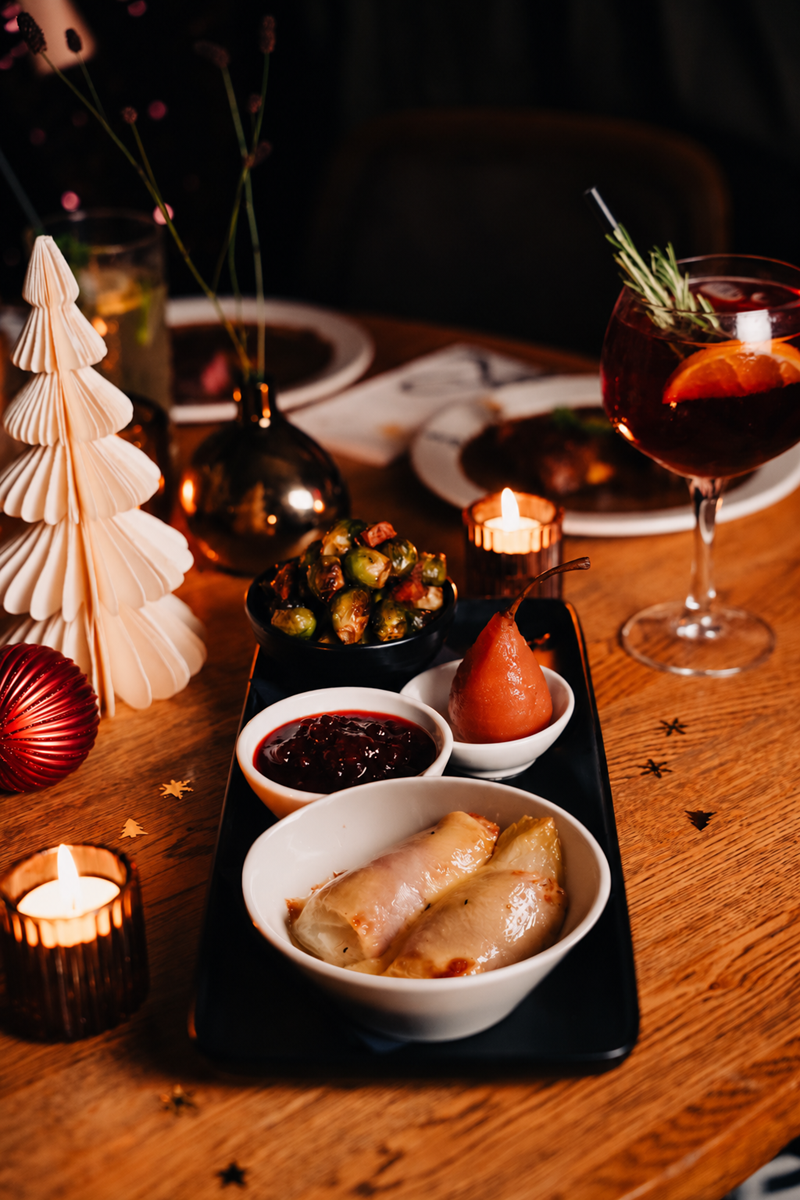 Loetje Kerstplateau met witlof, stoofpeer, cranberrycompote en spruitjes op een feestelijk gedekte tafel.